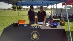 Two women staff pose behind National Night Out booth