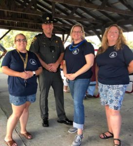 Three female staff members pose at picnic area with officer