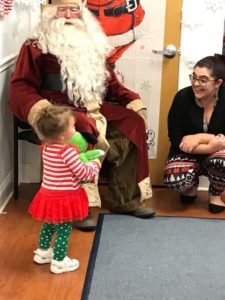 Seated Santa talking with young girl and smiling woman